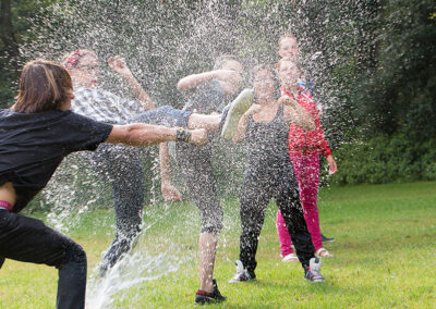 Een verzameling beelden van deelnemers en begeleiders die samen plezier maken, leren en nieuwe ervaringen opdoen tijdens kampactiviteiten in de buitenlucht.