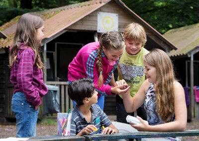 Een verzameling beelden van deelnemers en begeleiders die samen plezier maken, leren en nieuwe ervaringen opdoen tijdens kampactiviteiten in de buitenlucht.