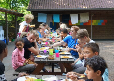Een verzameling beelden van deelnemers en begeleiders die samen plezier maken, leren en nieuwe ervaringen opdoen tijdens kampactiviteiten in de buitenlucht.